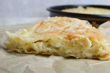 Traditional Balkan, Serbian cheese pie, phyllo dough, burek, borek, on the paper and burek pan in the background