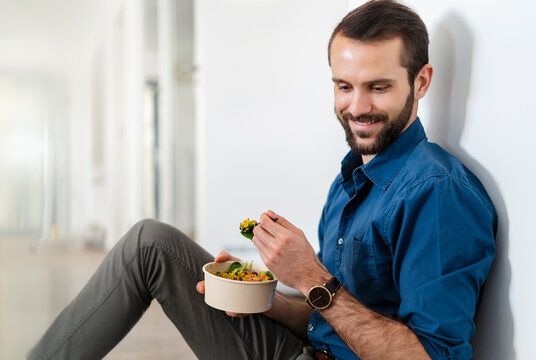 Smiling businessman having food while siting at office