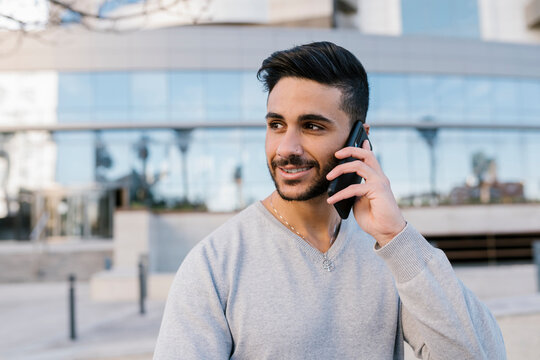 Handsome young man talking on smart phone while looking away