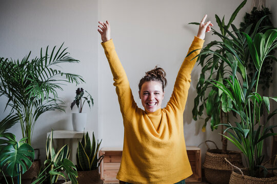 Carefree woman with hand raised sitting at home