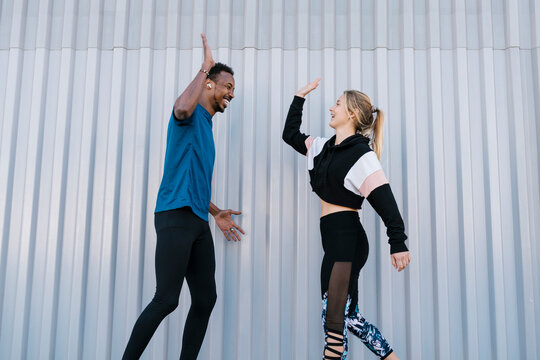 Cheerful male and female sportsperson giving high-five by wall