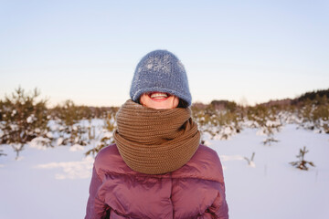Smiling woman face covered with knit hat against sky during winter