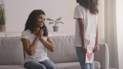 Happy Mother's Day celebration. Little african american girl congratulating her black mother with handmade postcard