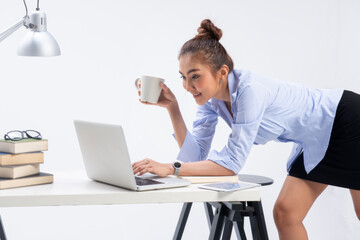 Trendy sexy business woman chatting on laptop and drink coffee in her office with attractive looks so beautiful.