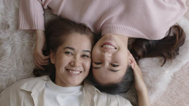 Attractive beautiful cheerful authentic real family two people laying down look at camera above tender emotion hug kiss cuddle relax comfort sleep in living room in health care healthy mother day.