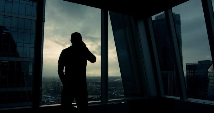 Silhouette of an young man that is talking at phone and walking inside the business building
