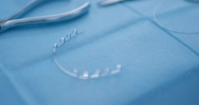 Close-up dental scissors, multiloop edgewise archwire, arch for the bracket system are laying in the disposable napkin.