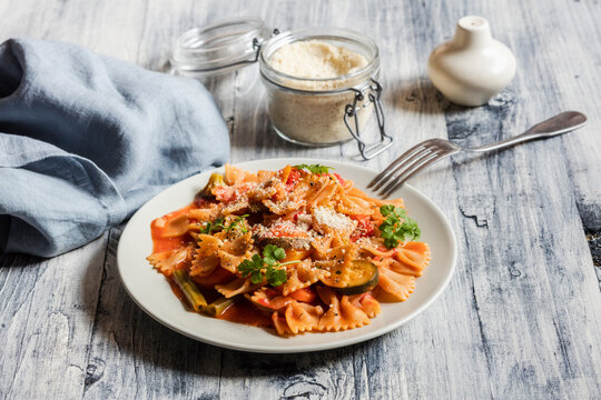 Two plates of bow tie pasta with vegetables and vegan Parmesan