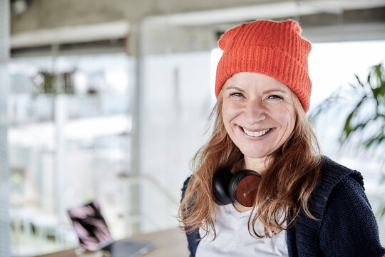 Smiling woman with knit hat at home
