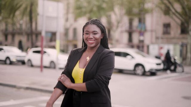 Cheerful stylish black woman walking on modern city street