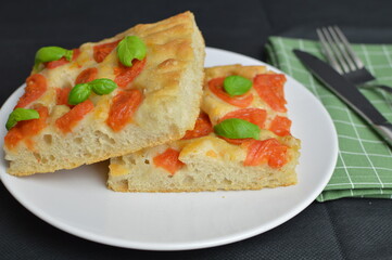 Italian focaccia  bread with tomatoes and basil on the white plate, two pieces