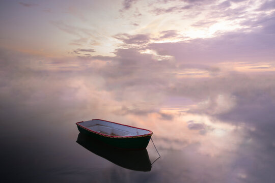 Boat moored on calm sea against cloudy sky during sunset