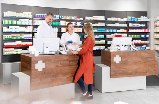 Female customer purchasing medicine from pharmacists in store