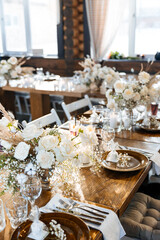 Decorations and flower arrangements made of gypsophila, roses and cotton. The concept of wedding decor in the winter season. Glass goblets and table setting. Selected focus and blurred background