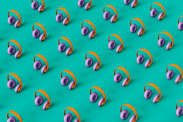 Multi colored headphones arranged in a line on green background