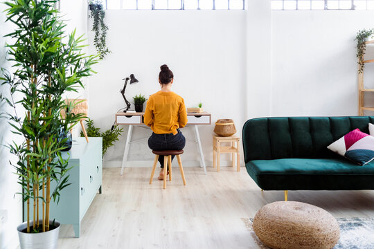 Young woman working while sitting on stool at home office