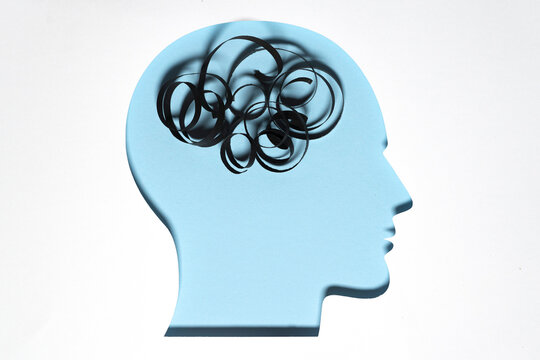 Paper cut out of human head with piece of string representing unordered thoughts