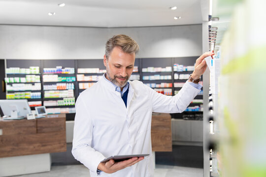 Male pharmacist doing inventory with digital tablet
