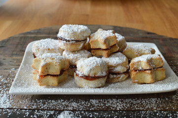 Traditional Serbian homemade sugar powered vanilla cookies with jam (vanilice) round and star shape, selective focus wooden table in background