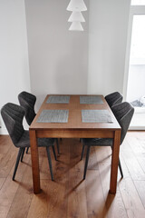 a brown textured wood kitchen table with four gray chairs stands on a brown wood floor
