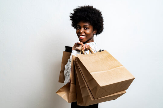 Smiling woman carrying shopping bags while standing against white background