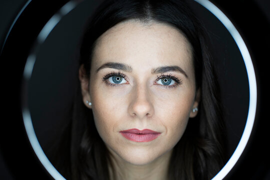 Woman with pink lipstick seen through ring light in studio