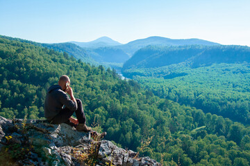 Naklejka na ściany i meble Man talking on a mobile phone on a mountain landscape background
