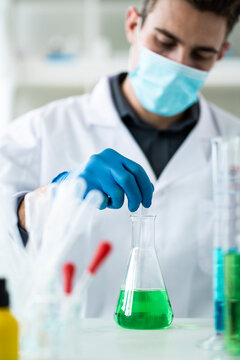 Young scientist making medicine in flask at laboratory during COVID-19