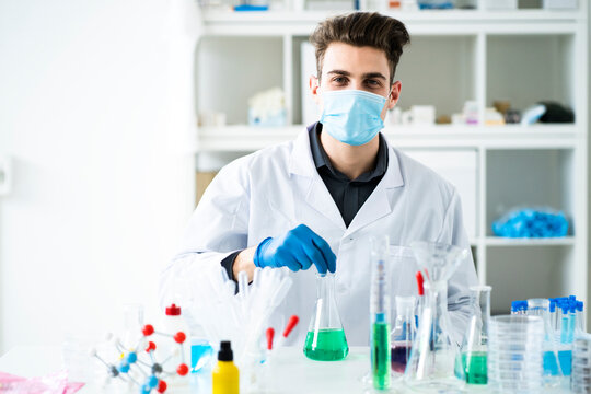 Male scientist wearing protective face mask while working in laboratory during pandemic