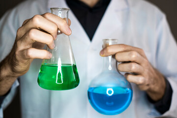 Scientist holding flasks with liquids in laboratory