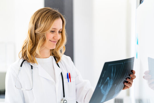 Smiling female doctor holding X-ray at medical clinic
