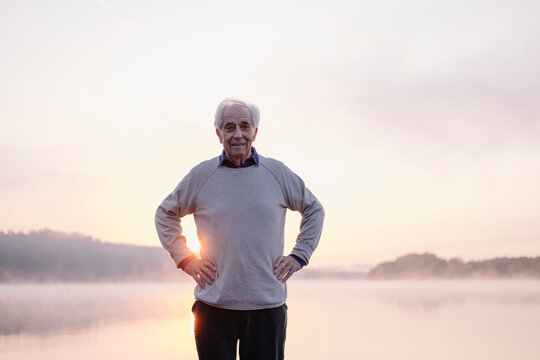 Smiling man standing with hand on hip against sky during sunrise
