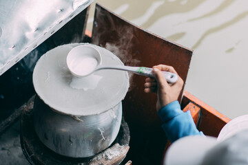 Fototapeta na wymiar The woman was pouring the flour onto a white cloth tied over the pot to cook.