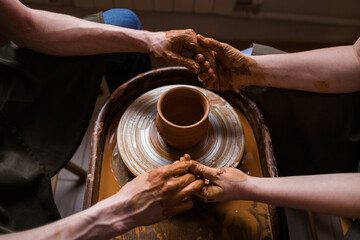 joined hands of a man and a woman near a loom with a clay pot