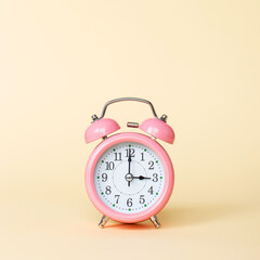 Pink alarm clock on a yellow background. Copy space.