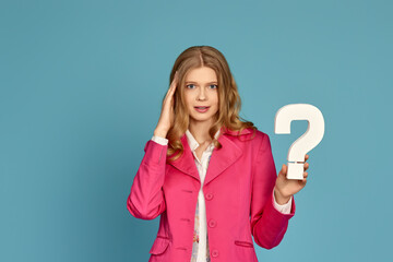 blonde woman in pink jacket holding question mark