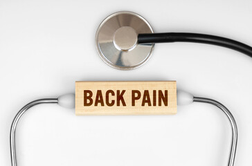 On the table is a stethoscope and a wooden plate with the inscription - BACK PAIN