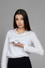 beautiful woman in shirt holding little white car