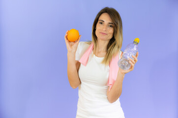 Healthy beautiful smiling young woman with pink towel on neck holding bottle with fresh water and...