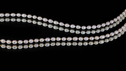 Lines of baroque pearls on black mirror background