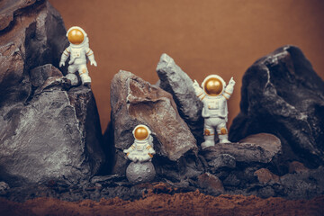 Astronaut with gold visor and White Spacesuit on rock surface with space background.
