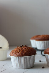 Chocolate muffins in paper forms on a gray background