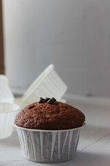 Chocolate muffins in paper forms on a gray background