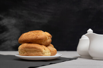 Lush homemade eclairs and tea-drinking utensils. French traditional baking