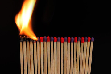 Burning matches standing in a row on a black background