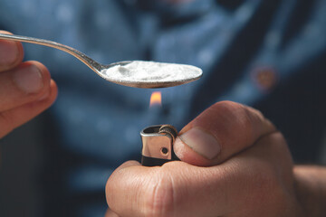 addict warms a spoon with powder