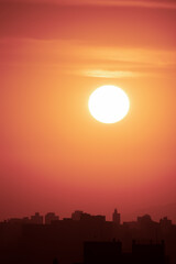 Obraz premium Por do Sol na cidade de São Paulo. Sol grande, fotografado em close up. Silhueta dos prédios da cidade. Espaço para texto. 