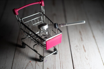 vaccine syringe vial of liquid on a shopping cart trolley showing online purchasing of medicine...