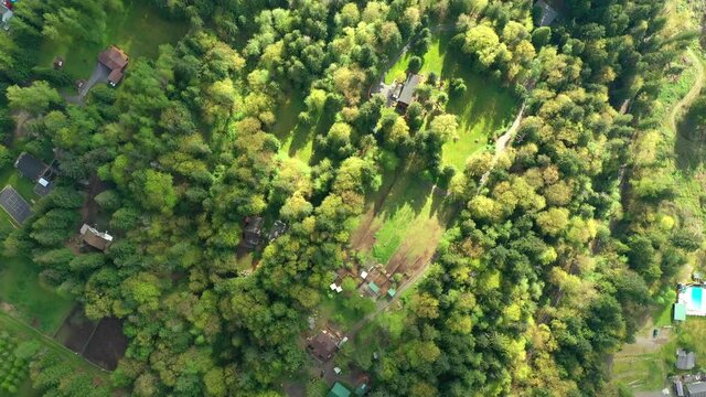 Flying Over Forested Hill with Houses Roof in View in the Pacific Northwest