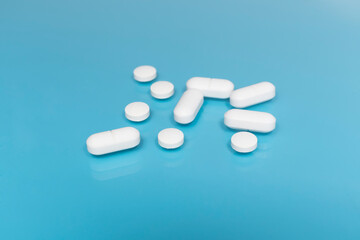 White pills and tablets on a blue medical table. The concept of taking antibiotics, antidepressants or other medications. Medical background. pharmacy concept